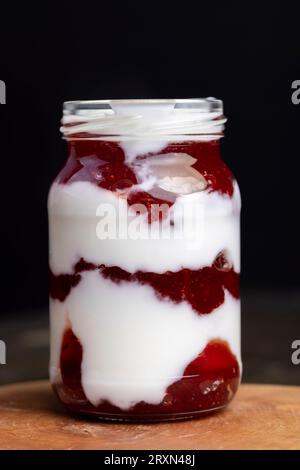 Yaourt fait à partir de lait frais avec l'ajout de confiture de fraise rouge sucrée, délicieux yaourt avec saveur de fraise Banque D'Images