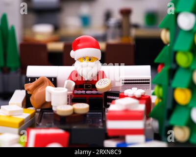 Tambov, Fédération de Russie - 24 septembre 2023 Une minifigurine Lego du Père Noël assise sur un canapé et mangeant des biscuits et du lait Banque D'Images