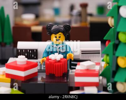 Tambov, Fédération de Russie - 24 septembre 2023 Une minifigurine Lego assise sur un canapé et ouvrant des cadeaux à Noël Banque D'Images
