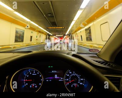 Une voiture descend dans le train Eurotunnel la nuit à Coquelles près de Calais en France avant d'être transportée sous la Manche à Folkes Banque D'Images