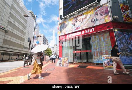 Une femme tenant un parapluie marche le long du trottoir à Ikebukuro, Tokyo, Japon Banque D'Images