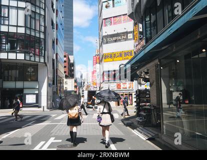 Deux filles japonaises conscientes de la mode marchent le long du trottoir à Ikebukuro, Tokyo, Japon Banque D'Images