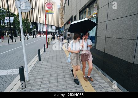 Deux filles japonaises conscientes de la mode marchent le long du trottoir à Ikebukuro, Tokyo, Japon Banque D'Images