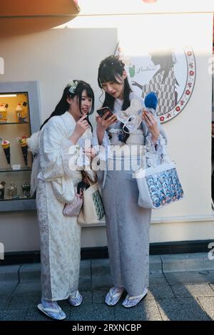 Deux japonaises vêtues de kimonos rient de photos sur un smartphone à Asakusa, Tokyo, Japon Banque D'Images