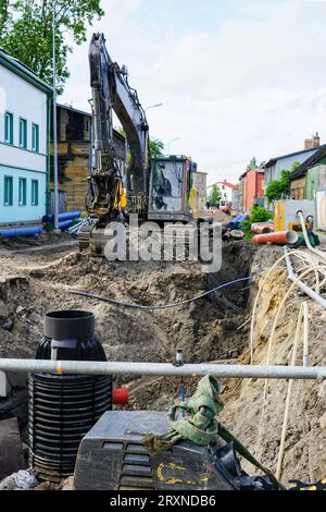 Vue de reconstruction de rue, tranchée profonde, système d'assèchement, nouveaux et anciens tuyaux, puits en plastique, excavatrice, remplacement de pipeline Banque D'Images