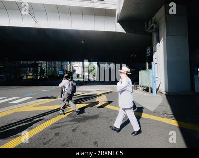 Un homme en costume blanc se tient sur le trottoir à Shimbashi, Tokyo, Japon Banque D'Images