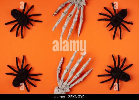 Araignées noires et mains de squelette sur orange, Halloween, fond Banque D'Images