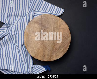 Planche à découper ronde en bois de cuisine sur fond noir, vue de dessus. Espace de copie Banque D'Images