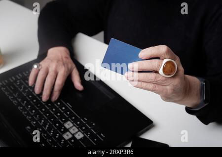 les mains de la femme plus âgée sur l'ordinateur portable avec carte de crédit Banque D'Images