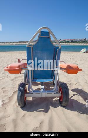 Fauteuil roulant de plage bleu sur sable prêt à l'emploi. Concept de tourisme accessible Banque D'Images