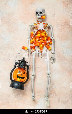 Savoureux cors de bonbons Halloween, squelette et lanterne sur fond beige Banque D'Images
