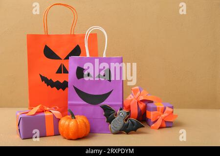 Composition avec des sacs à provisions, des boîtes cadeaux et un cookie savoureux pour Halloween sur fond beige Banque D'Images