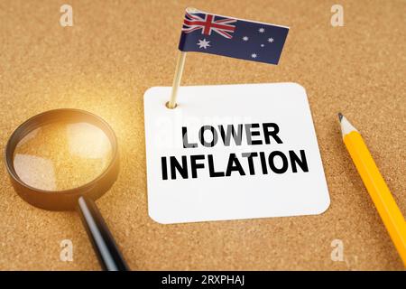 Concept d'économie et de finance. Sur la table se trouvent une loupe, un crayon, le drapeau de l'Australie et une feuille de papier avec l'inscription - plus bas Banque D'Images