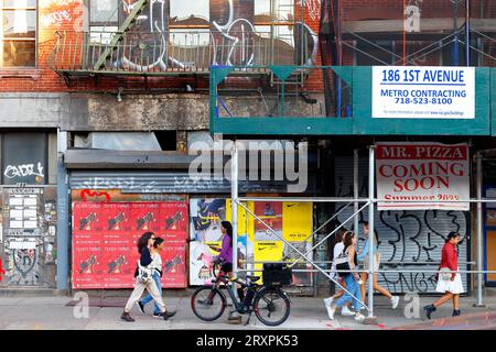 Des femmes, des gens marchant devant des bâtiments graffitis en rénovation et une pizzeria en construction dans East Village de Manhattan, New York. Banque D'Images