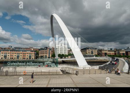 Newcastle upon Tyne, Royaume-Uni - 30 août 2023 : un seul individu marche devant le panneau Gateshead Millenium Bridge sur son chemin pour traverser Banque D'Images