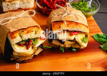 Sandwichs végétariens italiens grillés enveloppés dans du papier brun : sandwichs rustiques avec des ingrédients méditerranéens sur du pain focaccia grillé Banque D'Images