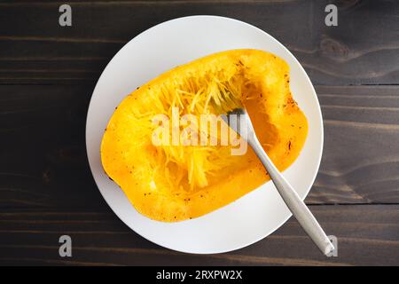 Déchiquetage d'une courge spaghetti avec une fourchette : la moitié de la courge spaghetti épétrie et cuite est râpée avec une fourchette Banque D'Images