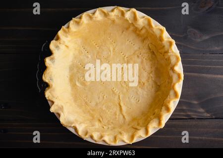 Pâte à tarte non cuite avec bords pincés dans un moule à tarte : pâte à tarte crue avec bords sertis dans un plat à tarte en céramique profond Banque D'Images