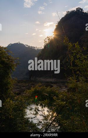 Les derniers rayons de soleil se cachant derrière les montagnes en forme de cône dans la région pittoresque de Wuyishan, Fujian, Chine. Image verticale avec espace de copie pour le texte Banque D'Images