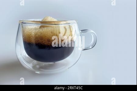 Gros plan café noir avec mousse naturelle en verre transparent à double paroi avec fond Uni, coup de pouce matinal, espresso, americano, torréfié foncé, ro Banque D'Images