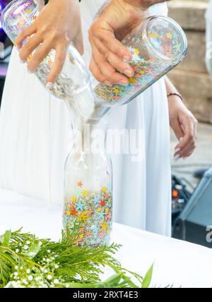 Un couple versant du sable dans un bocal en verre. Cérémonie de mariage Banque D'Images