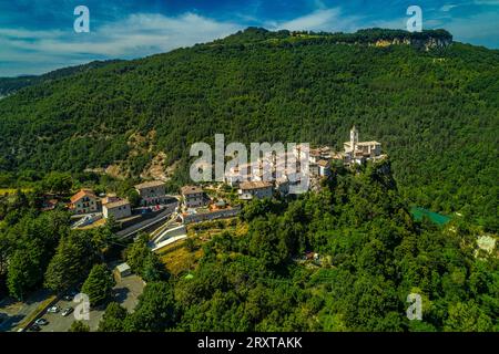 Vue aérienne de Castel Trosino entouré de bois verdoyants avec l'église de San Lorenzo Martire au sommet de la falaise de travertin. Région des Marches Banque D'Images