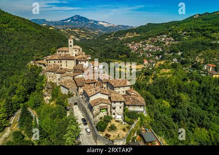 Vue aérienne de Castel Trosino entouré de bois verdoyants avec l'église de San Lorenzo Martire au sommet de la falaise de travertin. Région des Marches Banque D'Images