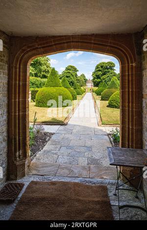 Yew Topiary dans le jardin de style Arts and Crafts vu à travers une arche à quatre centres au Lytes Cary Manor House médiéval près de Somerton, Somerton, Somerset, Angleterre Banque D'Images