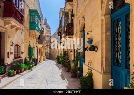 Bâtiments traditionnels maltais en calcaire avec balcons colorés dans les ruelles animées de la vieille ville de Birgu (Citta Vittoriosa), Malte Banque D'Images