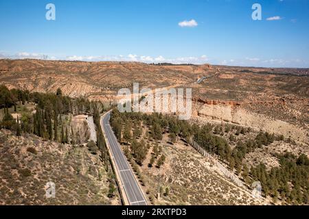 Drone vue aérienne d'une route traversant un paysage désertique près du barrage et réservoir Francisco Abellan, Grenade, Andalousie, Espagne, Europe Banque D'Images