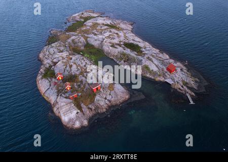 Maisons de bateau traditionnelles rouges et chalets sur une île rocheuse entourée par l'océan, Bohuslan, Suède occidentale, Scandinavie, Europe Banque D'Images