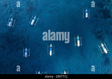 Aeria vue des bateaux de pêche traditionnels vides dans les eaux bleues de Gili Trawangan, îles Gili, Nusa Tenggara Ouest Banque D'Images
