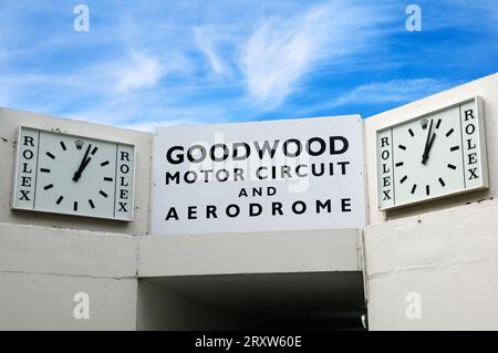 Signe vintage et horloges Rolex au-dessus du tunnel qui mène au circuit moteur et à l'aérodrome, Goodwood Revival festival, West Sussex, Angleterre, Royaume-Uni Banque D'Images