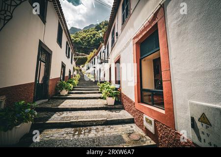 Vue panoramique sur une ruelle étroite avec des marches menant à la colline dans la petite ville de São Vicente sur Madère, Portugal Banque D'Images