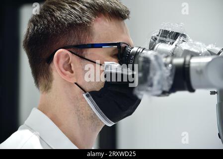 dentiste utilisant le microscope dentaire en clinique Banque D'Images