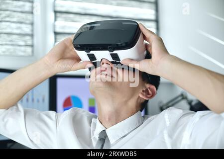 Boursier Homme portant Virtual Reality Googles. En regardant autour du graphique et du rapport de stock. Gros plan Banque D'Images