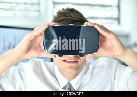 Jeune homme d'affaires portant Virtual Reality Googles. En regardant autour du graphique et du rapport de stock. Gros plan Banque D'Images