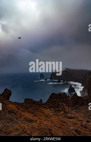 Vue du paysage rocheux de la péninsule de Ponta de São Lourenço à Madère, Portugal, par mauvais temps, avec un avion en approche d'atterrissage à Funchal Banque D'Images