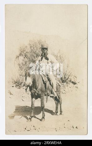 Carte postale photographique d'un homme avec une pipe, chevauchant une mule début du 20e siècle Banque D'Images