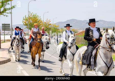 NERJA, ESPAGNE - 15 MAI 2022 femmes en robes flamenco et hommes sur des chevaux andalous vêtus de leurs meilleurs costumes folkloriques traditionnels et chapeau à large bord Banque D'Images