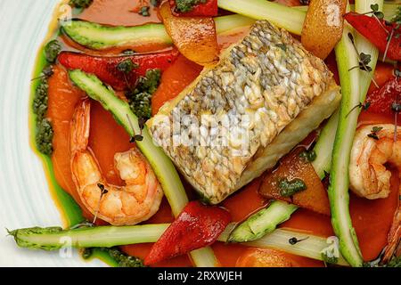 Steak de poisson frit avec crevettes et légumes sur fond sombre Banque D'Images