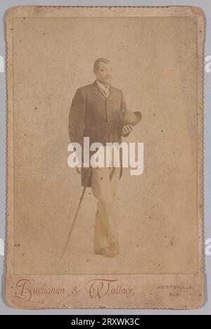 Photographie d'un homme en costume, appuyé sur une canne et tenant un chapeau à la fin du 19e siècle Banque D'Images