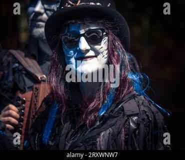 Morris danseurs avec le maquillage complet et les visages peints et jouant de l'accordéon. Costumes traditionnels de danse folklorique sombre avec chapeaux hauts et lunettes de soleil Banque D'Images