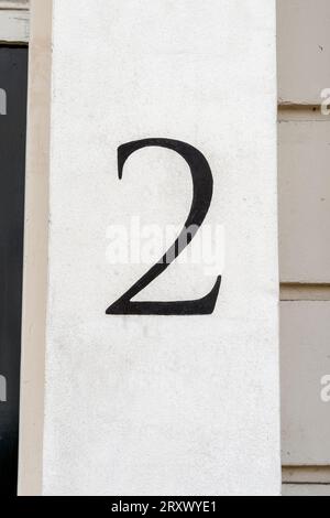 Numéro de porte numéro deux peint à la main en noir sur mur blanc Banque D'Images