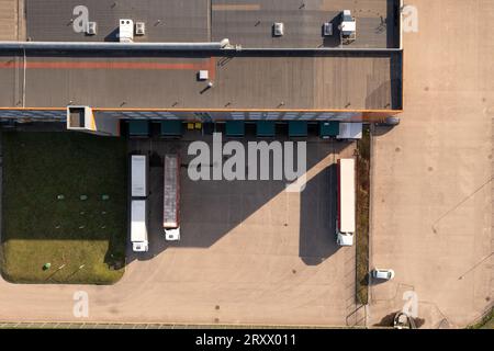 Photographie drone de l'entrepôt logistique et des camions pendant la journée ensoleillée. Directement au-dessus Banque D'Images