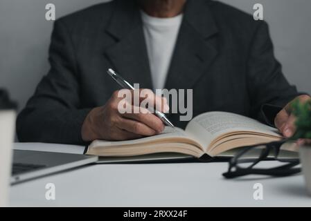 Femme mains avec stylo écrire sur le carnet dans le bureau.apprentissage, éducation et travail.écrit des objectifs, des plans, faire à faire et liste de souhaits sur le bureau. Banque D'Images