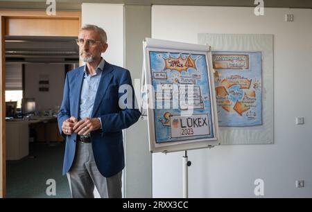 27 septembre 2023, Saxe, Dresde : Armin Schuster (CDU), ministre de l'intérieur de Saxe, se tient à côté d'une représentation visuelle de l'exercice interdépartemental de gestion de crise de LÜKEX au ministère de l'intérieur. Le scénario de l'exercice LÜKEX envisage des attaques contre l'action du gouvernement. Photo : Robert Michael/dpa Banque D'Images