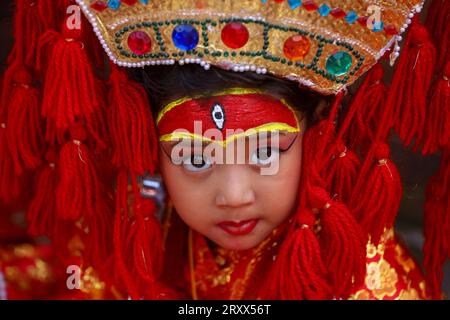 Kumari Pooja au Népal Une jeune fille népalaise pré-pubère pose pour une photo alors qu'elle assiste à la messe Kumari Pooja organisée à Basantapur Durbar Sqaure - un site du patrimoine mondial de l'UNESCO dans la capitale népalaise Katmandou. Vêtues de robes rouges, la déesse vivante Kumari Newa : les filles s'assoient en ligne pour être adorées tour à tour pour conjurer la malchance et les maladies. Les filles pré-pubères sont adorées chaque année inn la nation himalayenne comme incarnations terrestres de l'énergie féminine divine, manifestations de la déesse connue sous le nom Taleju Bhawani, le nom népalais de la déesse Durga. Droit d'auteur : xSubashxShresthax Banque D'Images