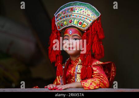 Kumari Pooja au Népal Une jeune fille népalaise pré-pubère pose pour une photo alors qu'elle assiste à la messe Kumari Pooja organisée à Basantapur Durbar Sqaure - un site du patrimoine mondial de l'UNESCO dans la capitale népalaise Katmandou. Vêtues de robes rouges, la déesse vivante Kumari Newa : les filles s'assoient en ligne pour être adorées tour à tour pour conjurer la malchance et les maladies. Les filles pré-pubères sont adorées chaque année inn la nation himalayenne comme incarnations terrestres de l'énergie féminine divine, manifestations de la déesse connue sous le nom Taleju Bhawani, le nom népalais de la déesse Durga. Droit d'auteur : xSubashxShresthax Banque D'Images