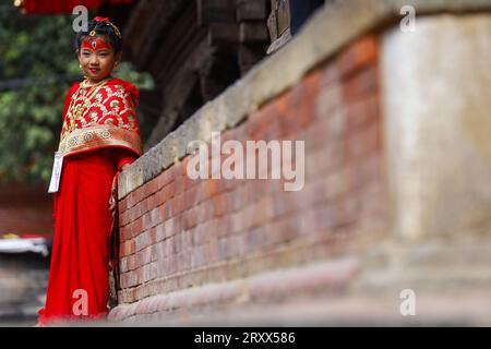 Kumari Pooja au Népal Une jeune fille népalaise pré-pubère pose pour une photo alors qu'elle assiste à la messe Kumari Pooja organisée à Basantapur Durbar Sqaure - un site du patrimoine mondial de l'UNESCO dans la capitale népalaise Katmandou. Vêtues de robes rouges, la déesse vivante Kumari Newa : les filles s'assoient en ligne pour être adorées tour à tour pour conjurer la malchance et les maladies. Les filles pré-pubères sont adorées chaque année inn la nation himalayenne comme incarnations terrestres de l'énergie féminine divine, manifestations de la déesse connue sous le nom Taleju Bhawani, le nom népalais de la déesse Durga. Droit d'auteur : xSubashxShresthax Banque D'Images